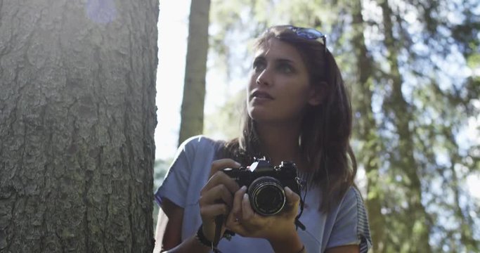 Woman photographer shooting photos with vintage camera in sunny forest.Group of friends summer adventure journey in mountain nature outdoors.Travel exploring Alps,Dolomites,Italy.4k slow motion 60p