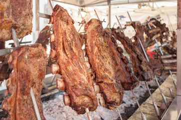 Roasted meat of beef cooking. Asado is traditional Argentine dish.