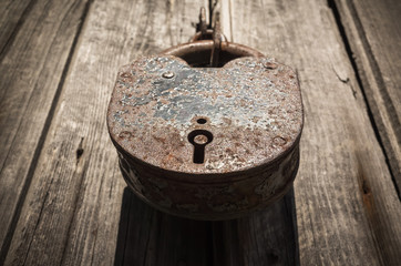 Old big rusted padlock hanging on wooden door