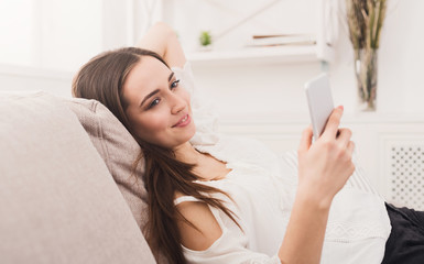 Obraz na płótnie Canvas Girl at home chatting online on smartphone