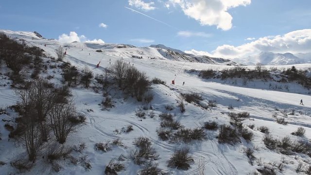 Aerial view from above of a snow covered alpine ski slope piste in winter resort while traveling uphill on mountainside