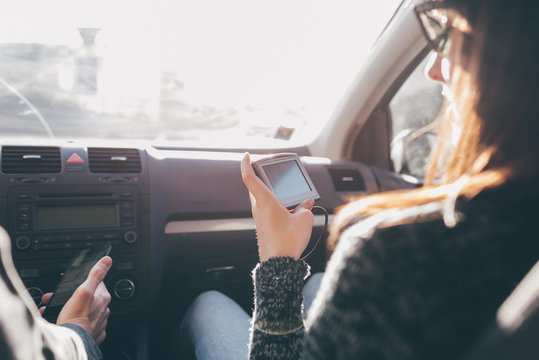 Over shoulder view of woman looking at sat nav in front seat of car