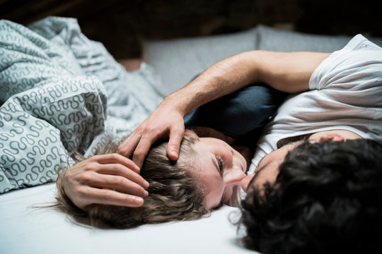 Young couple lying in bed embracing face to face