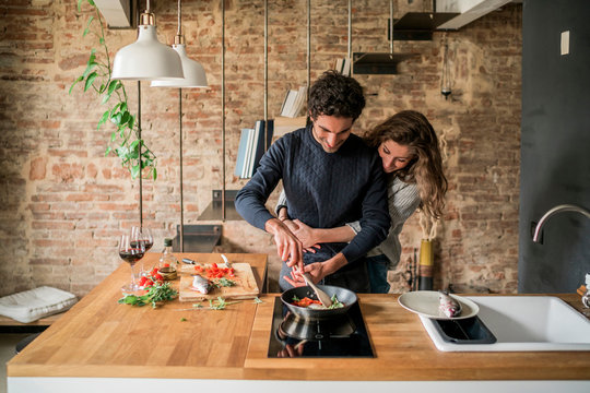 Young couple cooking fish cuisine at kitchen counter hob