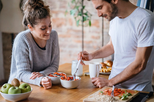 Young couple eating fruit breakfast at kitchen counter