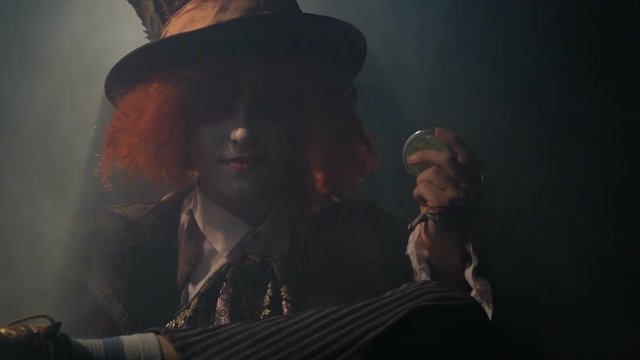 Mad hatter closes the hand mirror in the smoke