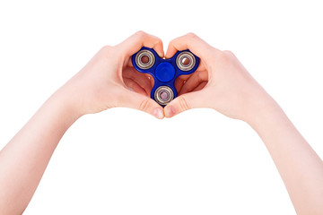 Hands of a child are holding a blue spinner, the child's fingers gesture a heart shape. A popular toy for concentration of attention, prevention of ADHD.