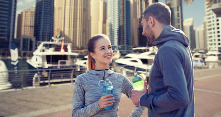 smiling couple with bottles of water in city