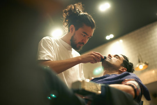Hairdresser in barbershop giving customer wet shave