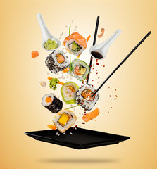 Flying sushi pieces served on plate, separated on colored background