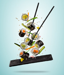 Flying sushi pieces served on plate, separated on colored background