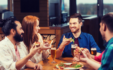 friends eating pizza with beer at restaurant
