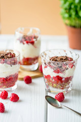 Homemade Dessert in Glass with Chocolate, Cream, Raspberry Jam and Pistachio on a Light Wooden Background, Vertical View