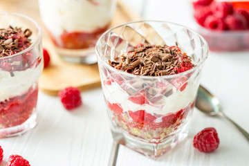 Homemade Dessert in Glass with Chocolate, Cream, Raspberry Jam and Pistachio on a Wooden Background