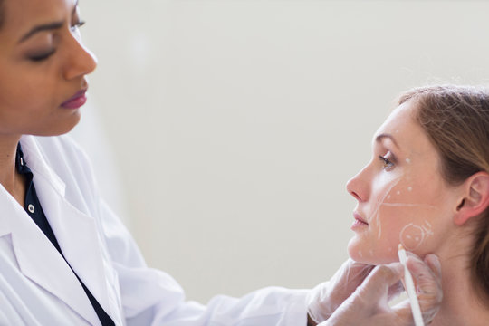 Cosmetic surgeon marking patient's face for surgery