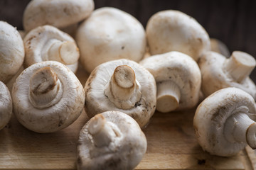 Fresh dirty Agaricus or сhampignon mushroom before peel on the wooden table