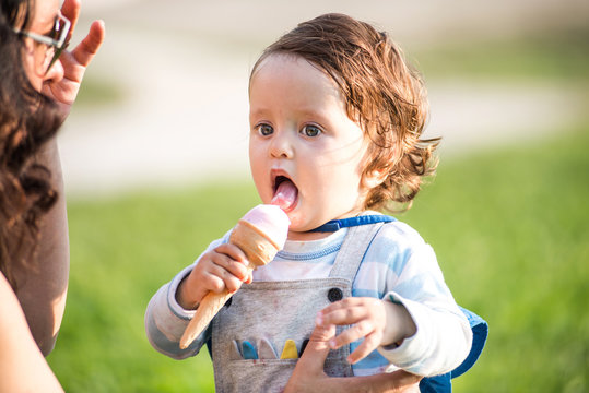 Woman with toddler son eating ice cream cone in park