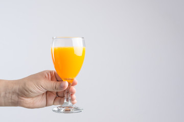 Hand holding glass of orange juice