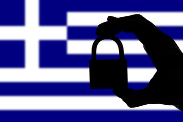 Greece security. Silhouette of hand holding a padlock over national flag