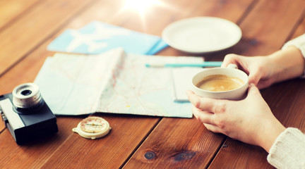 close up of hands with coffee cup and travel stuff