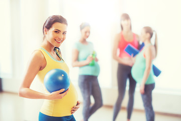 happy pregnant woman with ball in gym