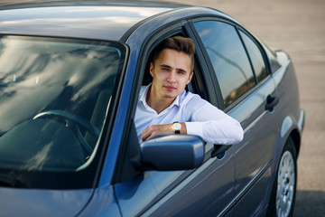 Fototapeta na wymiar Attractive handsome successful man in white shirt driving an expensive car