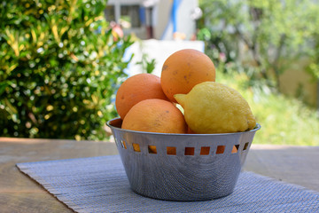 Oranges and lemons lie in a cup on the table