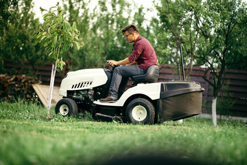 Worker using professional grass trimmer, lawn mower