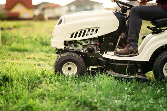 Gardner On Mower Doing Landscaping Works And Cutting Grass. Professional Worker Mowing Lawn