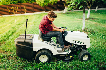 Industrial worker, handyman trimming grass using lawn mower