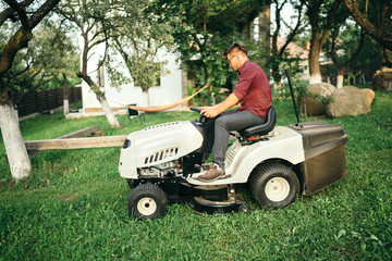 Fototapeta premium Male worker using garden lawn mower and cutting grass