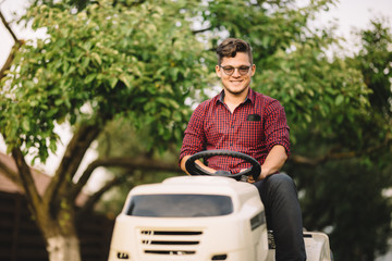 backyard lawncare man portrait - Smiling worker using ride on grass mower