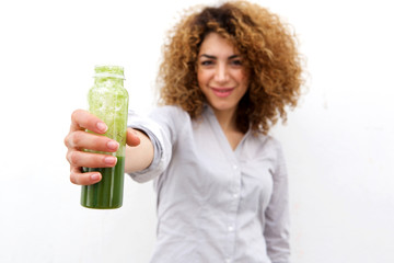 beautiful woman with curly hair holding bottle of green juice