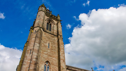 Fototapeta premium Square church tower against a blue sky with white clouds