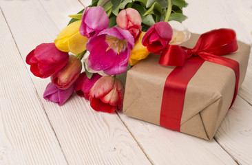 Obraz na płótnie Canvas bouquet of tulips with a gift on rustic wooden board