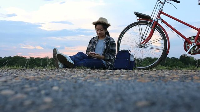 Bicycle and young hipster woman sitting playing touch smartphone using login social media.