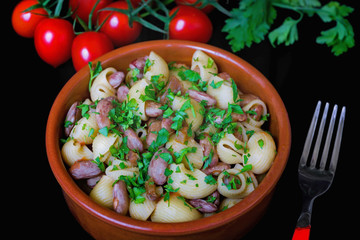 Pasta and beans, bowl on a black background.