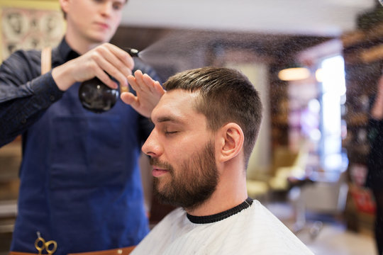 barber applying styling spray to male hair