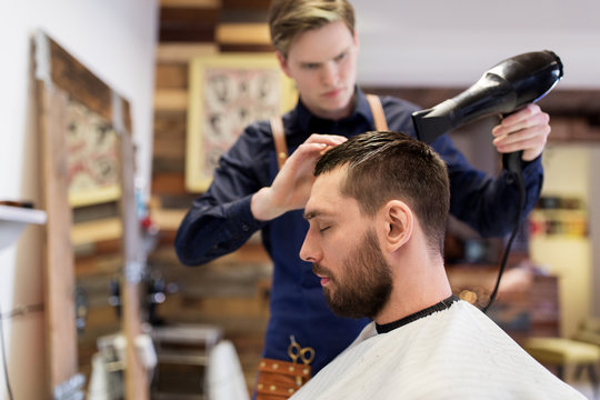 barber with fan drying male hair at barbershop