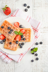 Waffles with fresh berries on wooden background, top view