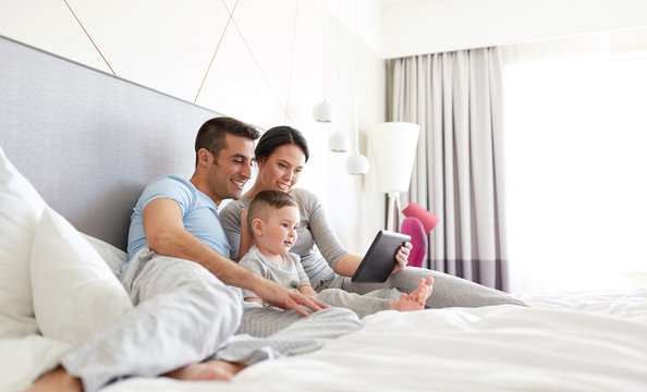 Happy Family With Tablet Pc In Bed At Home