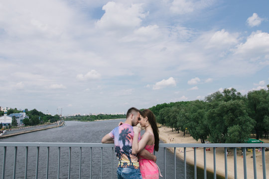 Young couple hugging and smiling each other walking on a bridge