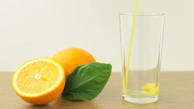 Fresh citrus fruits. Video footage of the concept of a healthy food and diet. Orange juice is poured into the glass, and sliced oranges with a leaf next.