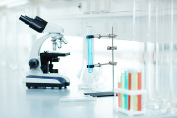 Various research equipment: electronic microscope and test tubes with colored liquid on table in medical laboratory