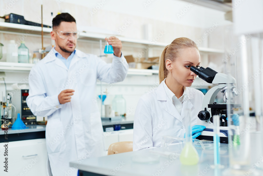 Wall mural portrait of two scientists, man and woman, working in modern laboratory, performing bio chemical res