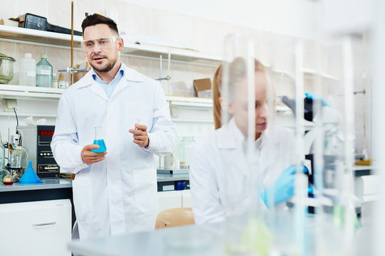 Portrait of two scientists, man and woman, working with test tubes in modern laboratory, performing research