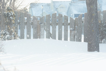 Snow falling near a garden gate in a residential neighborhood.