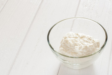 Cottage cheese in a glass bowl on a white table