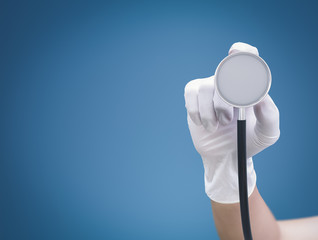 hand with rubber glove holding stethoscope