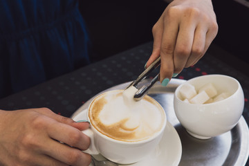 A very beautiful business woman sits in a cafe and holds a cup of coffee in her hands